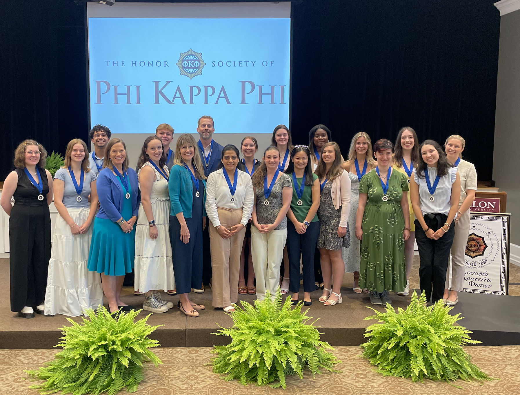 A group of people poses for a photo with a presentation screen that says 